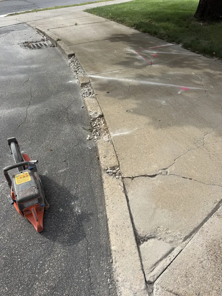 Damaged sidewalk and driveway edge before repair